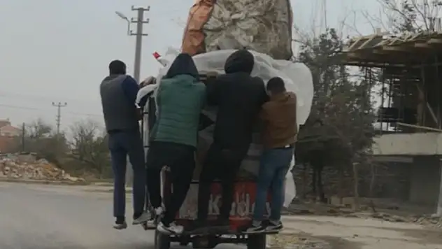 Şiddetli rüzgarda triportör devrilmesin diye üzerine binip gittiler
